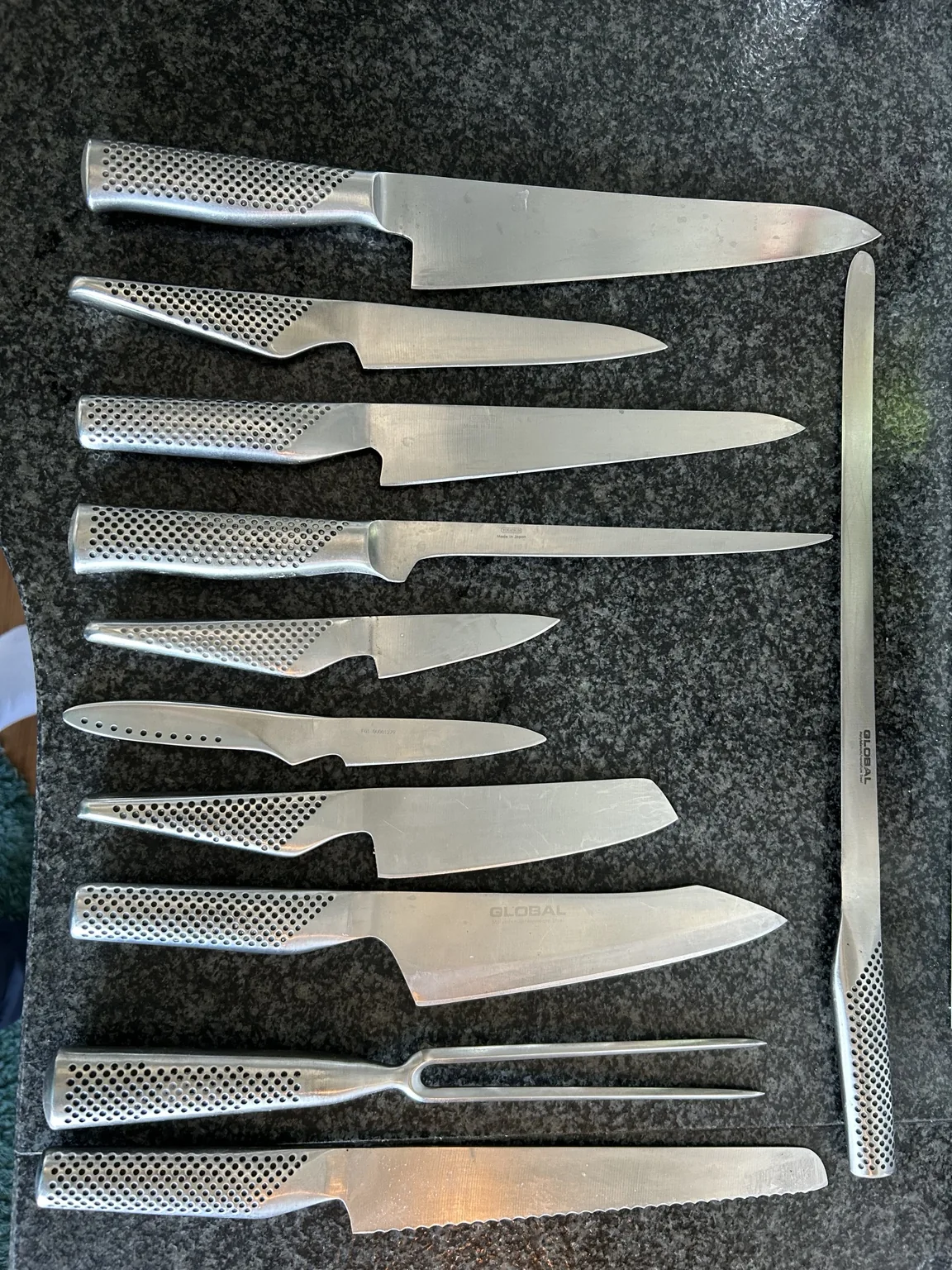 Min samling Global-köksknivar utlagda på köksbänken, med kockknivar, mindre knivar, brödkniv och stekgaffel